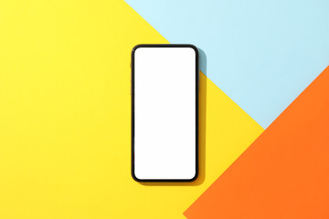 Phone with empty screen on multicolored background, top view