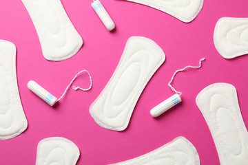 Sanitary pads and tampons on pink background, top view
