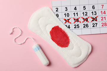Tampon, used sanitary pad and calendar on pink background, top view