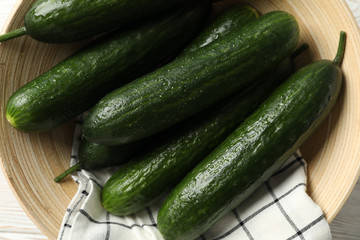 Bowl with cucumbers on wooden background, top view