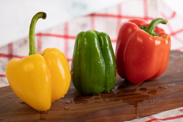 Tricolor peppers on a wooden board