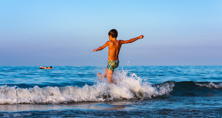 Child has fun and relaxes with the waves of the sea.