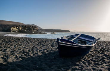 Fototapeta na wymiar Small boat on black beach in Ajuy, Fuerteventura, Canary Islands