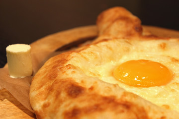 Process of cooking traditional adjarian georgian and armenian cuisine, hachapuri khachapuri with suluguni cheese and egg yolk on a wooden table with chief's hands in the background