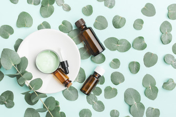 Eucalyptus cosmetic background. Cream, lotion and oil on paper background with fresh foliag on it. Top view, flat lay, mock up with copy space