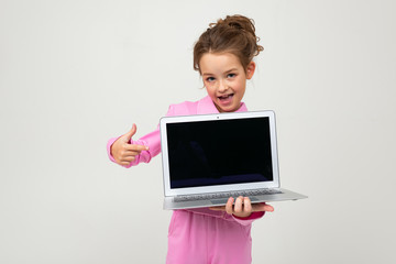 Closeup portrait of an attractive young girl in a pink suit showing a laptop screen with a mockup on a white background