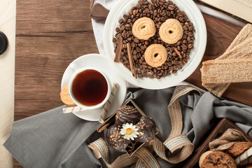 Cookies on coffee beans in a saucer and a cup of tea. top view