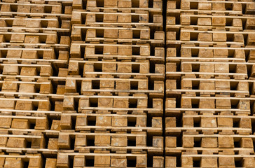 View on the stack of shipping wooden pallets stacked high on top of each other for logistic use. 