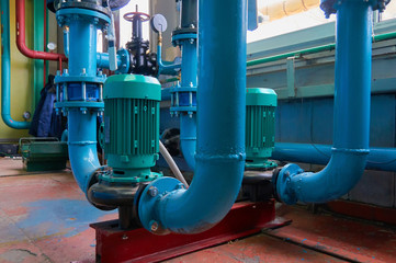 Green vertical motors with pumps on a blue colored water pipeline.