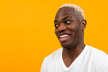 charismatic african man in a white t-shirt with a mock looks surprised to the side on a yellow studio background with copy space