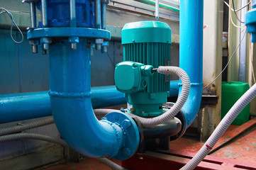 Green vertical motors with pumps on a blue colored water pipeline.