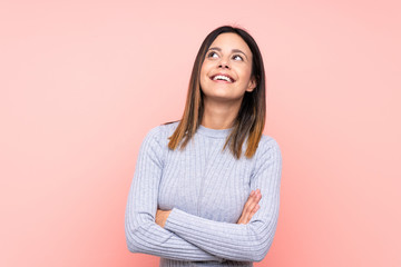 Woman over isolated pink background looking up while smiling
