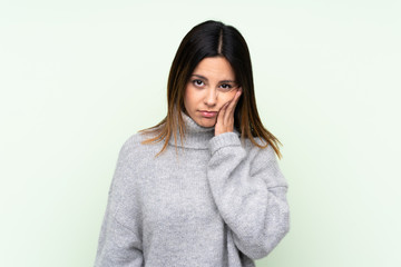 Woman wearing a sweater over isolated green background unhappy and frustrated