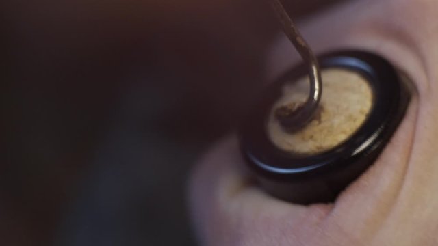Young man in classic suit opens bottle of red wine, close up, slow motion
