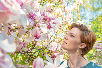 Portrait of young woman near blooming magnolia