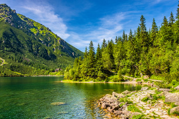Morskie Oko mountain lake, surrounding forest, Miedziane and Opalony Wierch peaks with Schronisko przy Morskim Oku shelter house in background in Tatra Mountains in Poland
