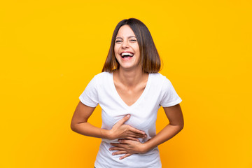 Obraz premium Young woman over isolated yellow background smiling a lot