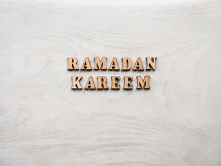 Wooden letters of the alphabet in the form of the words RAMADAN KAREEM lying on the table. Beautiful card. Isolated background, wooden surface. Congratulations for relatives, friends, colleagues