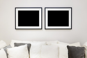 Two photo frame gallery mockup for poster image design on white wall with comfortable sofa furniture and scatter cushion in living room modern apartment scandinavian concept style