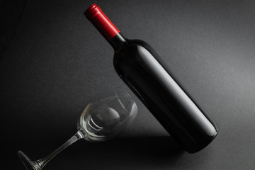 Red wine bottle mockup and glass on black background.