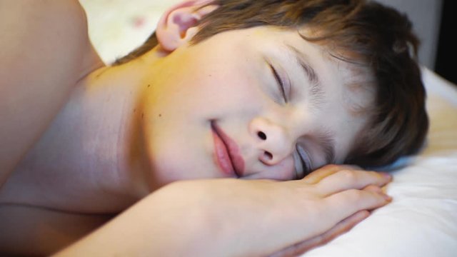 cute boy of school age, lies in bed and smiling.closeup