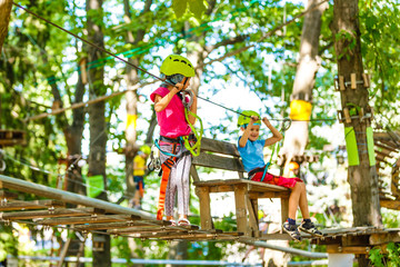Fototapeta na wymiar happy little children in a rope park on the wood background