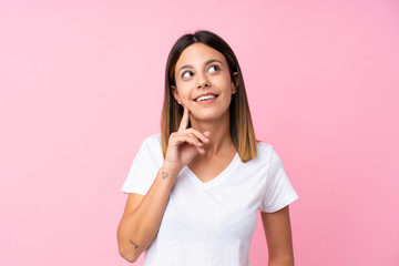 Young woman over isolated pink background thinking an idea while looking up
