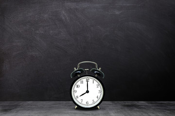 Time Management Concept : Retro black alarm clock showing eight o'clock with chalkboard background.