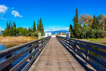 Fototapeta premium Wooden boardwalk to the Monastery of St. Nicholas in Lake Vistonida, Porto Lagos, Xanthi regional unit, Greece on a sunny winter day