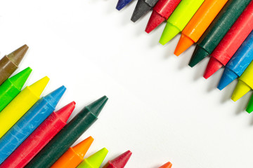 Colourful bright wax pencils on the right and left corner composition isolated on white and free space in the centre.