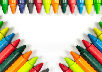 Colourful bright wax pencils isolated on white and free space in the centre of composition.