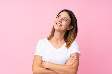 Young woman over isolated pink background looking up while smiling