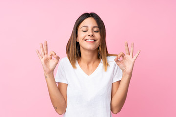 Young woman over isolated pink background in zen pose
