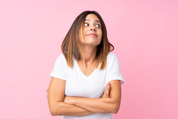 Young woman over isolated pink background making doubts gesture while lifting the shoulders