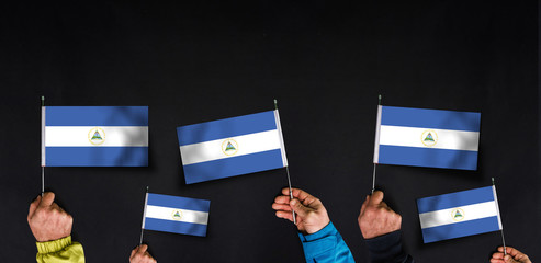 Hands holds flags of Nicaragua  on dark background