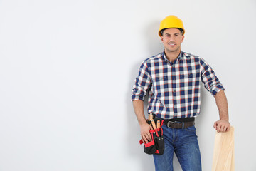 Handsome carpenter with wooden planks on light background. Space for text