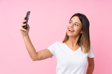 Young woman over isolated pink background making a selfie