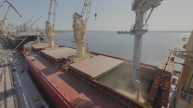 loading grain into a cargo ship for transportation by sea. The ship is loaded with wheat in the port. Wheat export. Sea export. Agriculture
