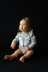 little girl sitting on a black background