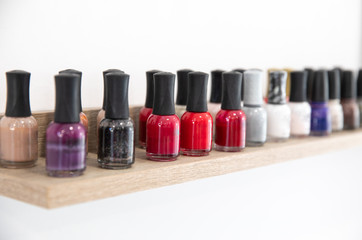 Nail polishes of different colors on shelf in the modern beauty salon isolated on white background.