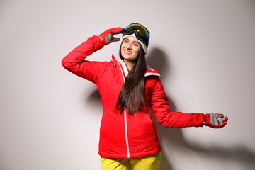 Woman wearing stylish winter sport clothes on light grey background