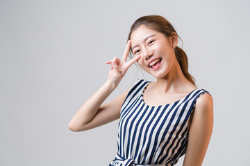 Young Asian woman smiling and raising her hand like victory or winner, feeling successful and happiness life on grey background.