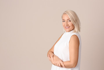 Naklejka premium Portrait of beautiful mature woman on beige background. Space for text