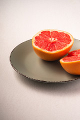 Fototapeta na wymiar Grapefruit two half on grey plate, tropical creative minimal food fruit concept, on white background, vibrant colors, angle view selective focus