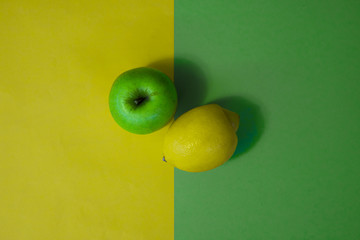Fruit on green and yellow background, lemon and apple minimalist texture flatlay, vegan organic healthy food