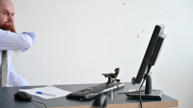 A bearded man is having a nervous breakdown at work. The office manager freaks out and breaks a mug on the monitor.
