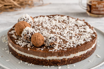 chocolate cake on a plate. Chocolate and coconut cake on a white wooden background. Foodfoto in a high key. Raw dessert