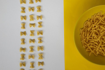 Bowl of fusilli pasta and farfalle pattern background, space for text