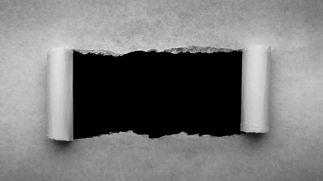 Creative 4k time laps video of a glowing full moon in the night sky with floating clouds, which is visible through a hole with torn edges in old retro grunge vintage paper.