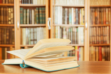 The open book is on the table in the background of the library.